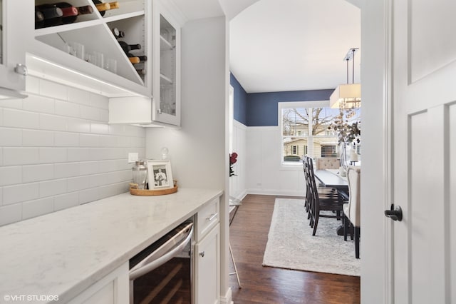 kitchen with light stone countertops, white cabinetry, decorative light fixtures, dark wood-type flooring, and beverage cooler