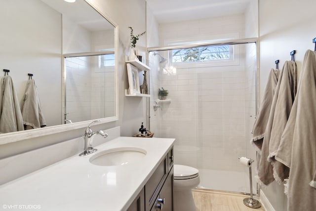 bathroom featuring an enclosed shower, large vanity, and toilet