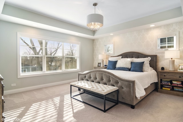 carpeted bedroom featuring an inviting chandelier and a raised ceiling