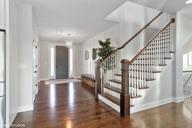 foyer entrance with an inviting chandelier and dark wood-type flooring