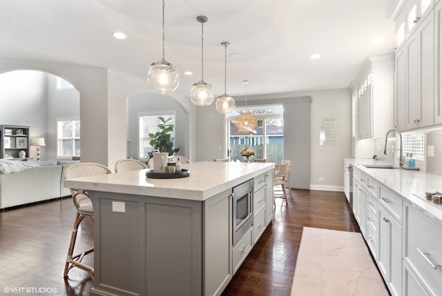 kitchen featuring a kitchen breakfast bar, hanging light fixtures, a kitchen island, and dark hardwood / wood-style flooring