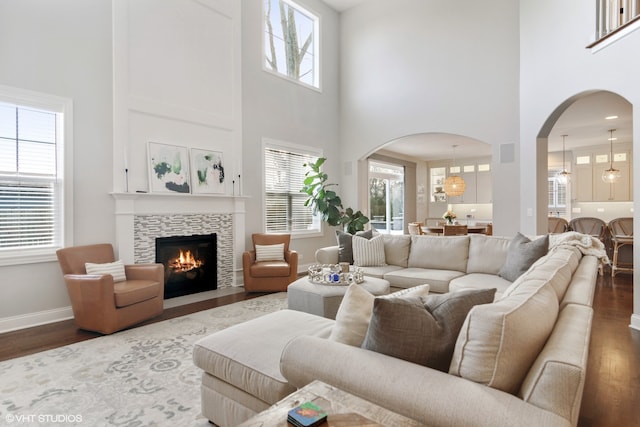 living room featuring a high ceiling, dark wood-type flooring, and a fireplace