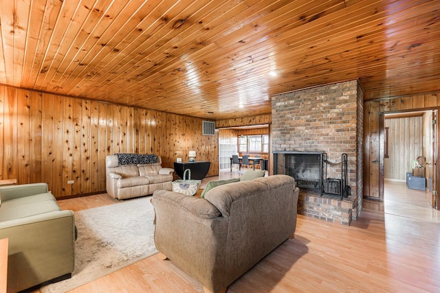 living room featuring wooden walls, visible vents, wooden ceiling, wood finished floors, and a brick fireplace