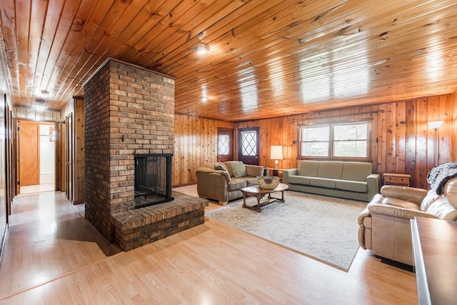 living room featuring wood ceiling, a fireplace, wooden walls, and wood finished floors