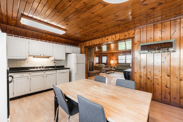 dining space featuring light wood-type flooring, wood walls, and wood ceiling