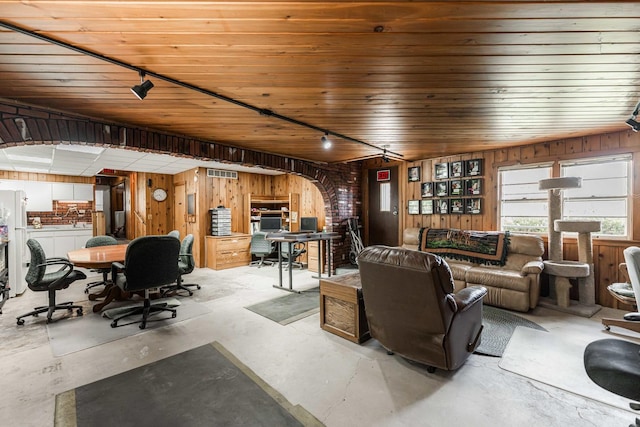 living room with concrete flooring, track lighting, visible vents, and wooden walls