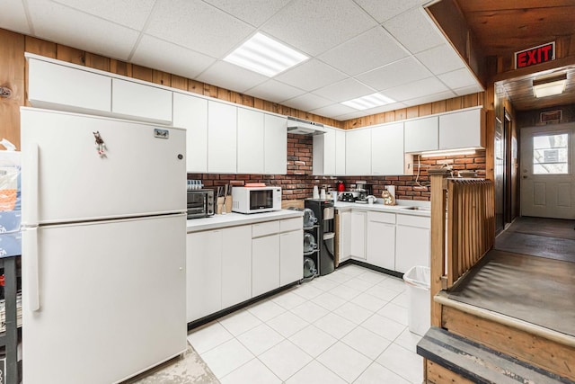 kitchen with light countertops, white appliances, a drop ceiling, and white cabinetry