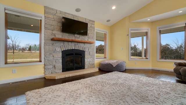 living room featuring hardwood / wood-style floors, a stone fireplace, and vaulted ceiling