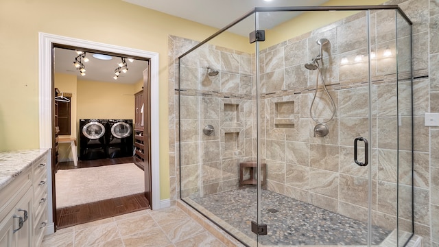 bathroom with tile flooring, an enclosed shower, washing machine and clothes dryer, and vanity