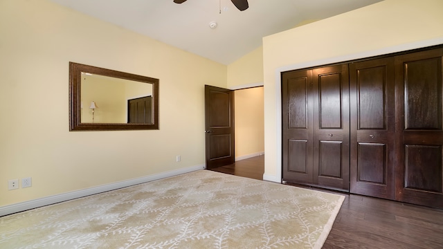 unfurnished bedroom with a closet, ceiling fan, lofted ceiling, and dark wood-type flooring