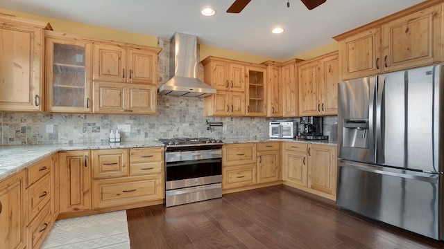 kitchen with stainless steel appliances, wall chimney range hood, light stone countertops, ceiling fan, and dark hardwood / wood-style flooring