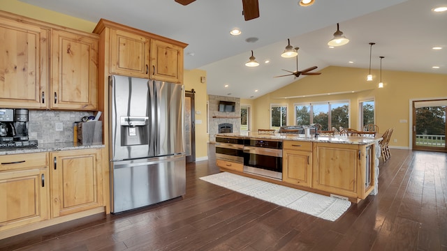 kitchen with dark hardwood / wood-style floors, ceiling fan, stainless steel appliances, a fireplace, and light stone countertops