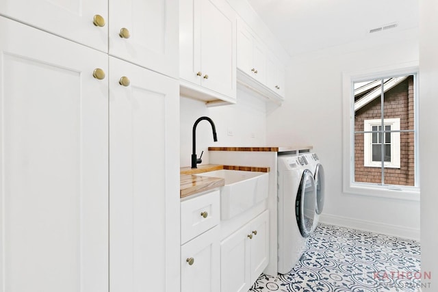 clothes washing area with sink, light tile flooring, cabinets, and separate washer and dryer