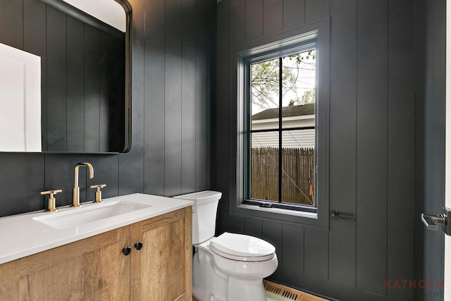 bathroom featuring vanity, toilet, and wooden walls