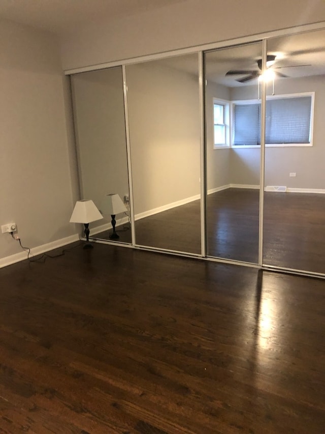 unfurnished bedroom with a closet, ceiling fan, and dark hardwood / wood-style flooring