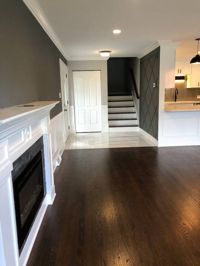 unfurnished living room featuring ornamental molding, sink, and light wood-type flooring