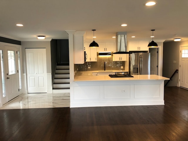 kitchen featuring hanging light fixtures, backsplash, hardwood / wood-style flooring, white cabinetry, and stainless steel fridge with ice dispenser