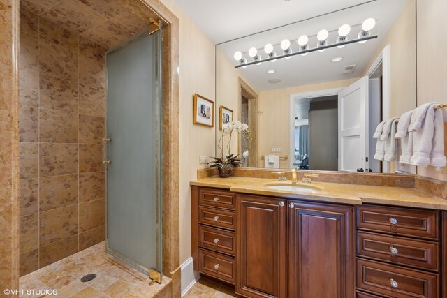 bathroom with tile flooring, vanity, and tiled shower