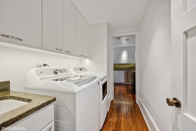 clothes washing area featuring dark hardwood / wood-style floors, cabinets, and independent washer and dryer