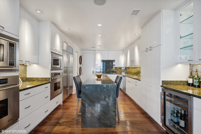 kitchen with wine cooler, white cabinets, dark hardwood / wood-style flooring, and built in appliances