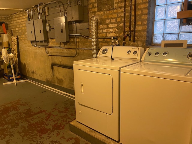 laundry area featuring brick wall, washer hookup, and washer and clothes dryer