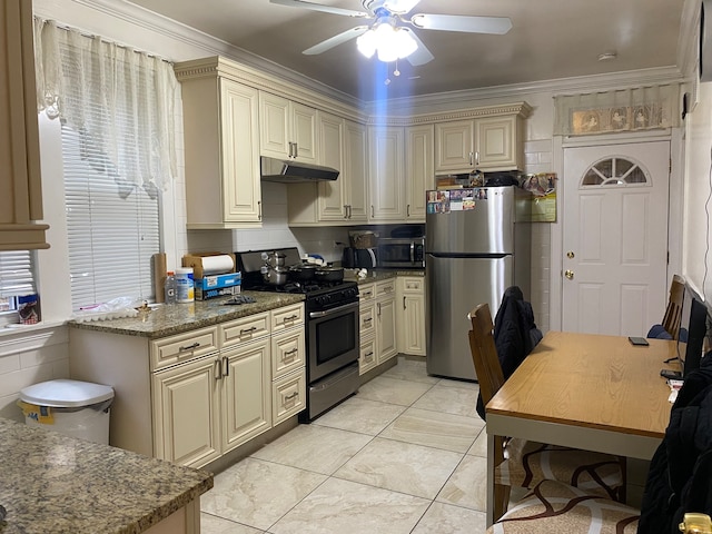 kitchen with dark stone countertops, ceiling fan, cream cabinets, and stainless steel appliances