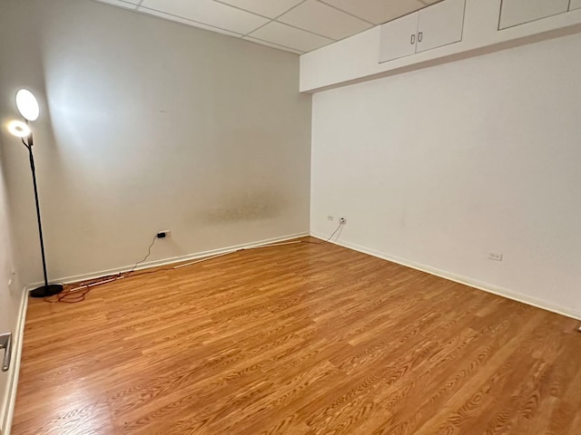 empty room with light wood-type flooring and a paneled ceiling