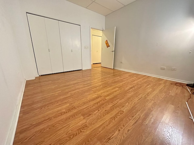 unfurnished bedroom featuring a paneled ceiling and light wood-type flooring