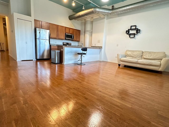 kitchen featuring rail lighting, a high ceiling, stainless steel appliances, and hardwood / wood-style floors