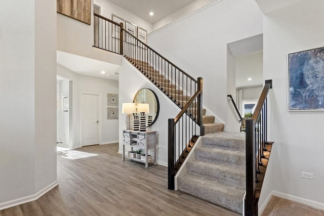 stairs featuring a towering ceiling and hardwood / wood-style flooring