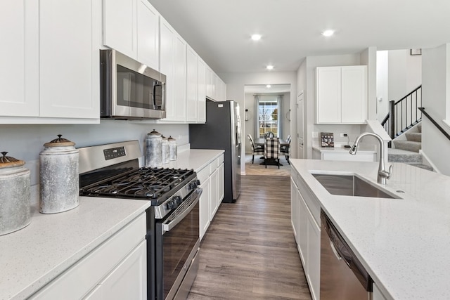 kitchen featuring sink, light stone counters, stainless steel appliances, white cabinetry, and hardwood / wood-style flooring