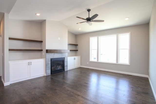 unfurnished living room with a tile fireplace, ceiling fan, and dark hardwood / wood-style floors