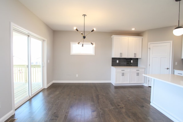 kitchen with tasteful backsplash, dark hardwood / wood-style flooring, hanging light fixtures, and white cabinets