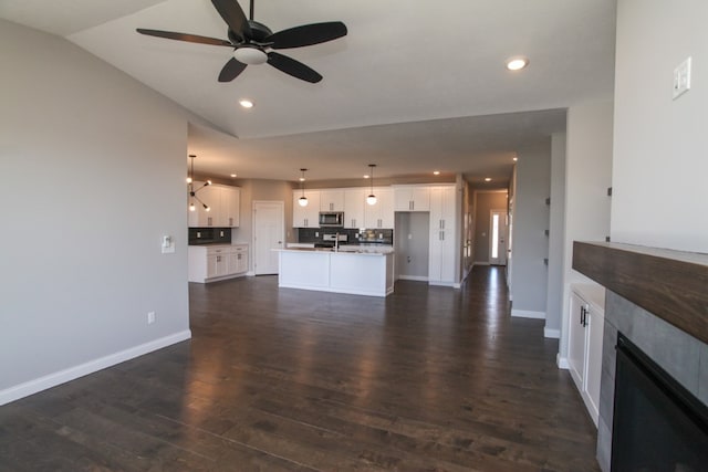 unfurnished living room with ceiling fan, a tile fireplace, sink, dark hardwood / wood-style flooring, and lofted ceiling