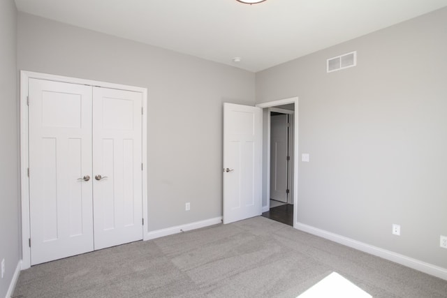 unfurnished bedroom with light colored carpet and a closet