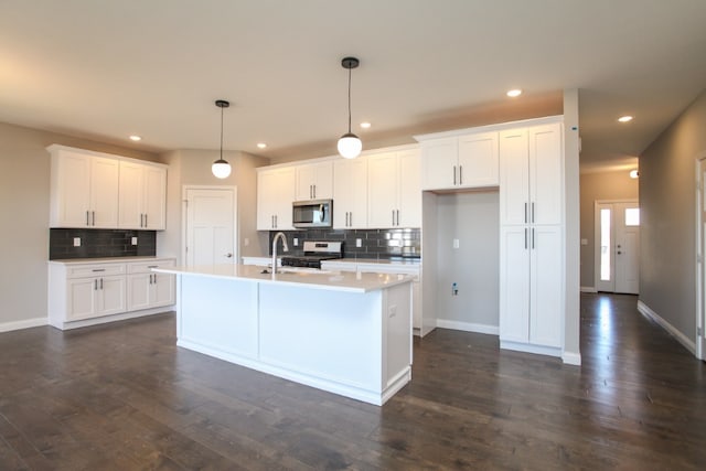 kitchen featuring white cabinets, appliances with stainless steel finishes, pendant lighting, and dark hardwood / wood-style floors