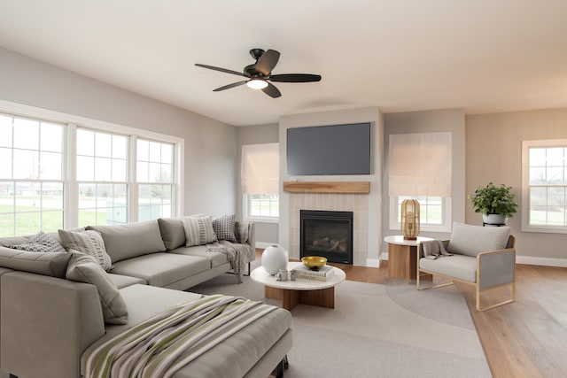 living room with a healthy amount of sunlight, ceiling fan, a fireplace, and light hardwood / wood-style flooring