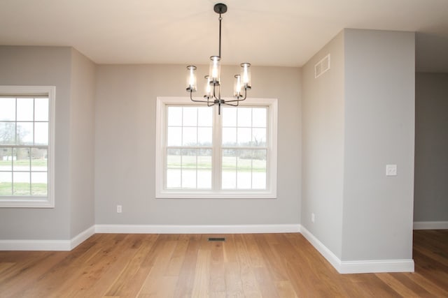 spare room featuring a notable chandelier and light wood-type flooring