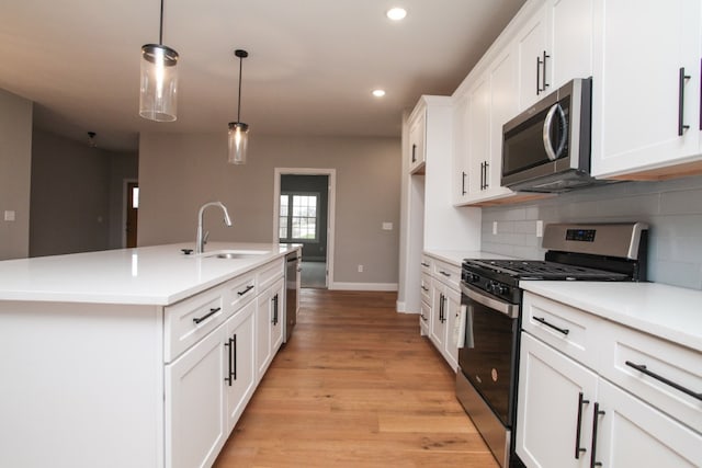 kitchen featuring a kitchen island with sink, sink, light hardwood / wood-style floors, stainless steel appliances, and white cabinetry