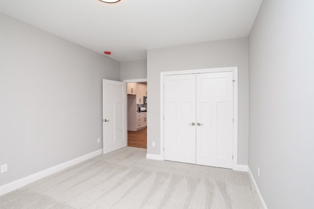 unfurnished bedroom with a closet and light colored carpet