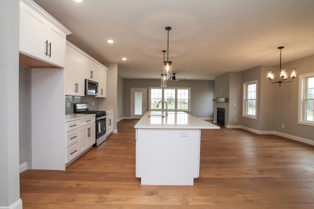 kitchen featuring a center island with sink, light hardwood / wood-style flooring, stainless steel appliances, and white cabinetry