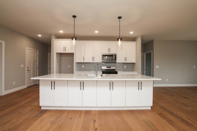 kitchen with white cabinets, appliances with stainless steel finishes, backsplash, and light hardwood / wood-style flooring