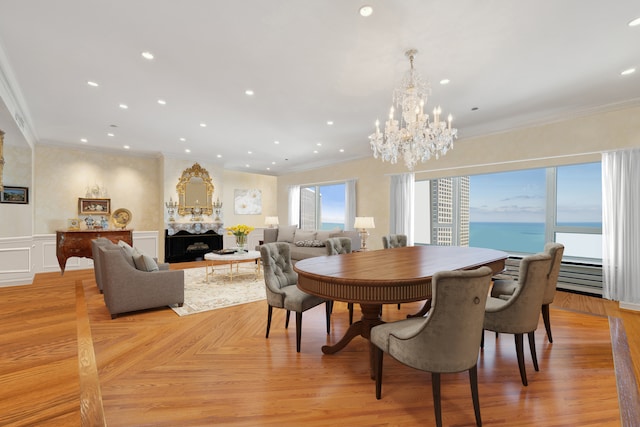 dining room with a water view, light parquet flooring, crown molding, and an inviting chandelier