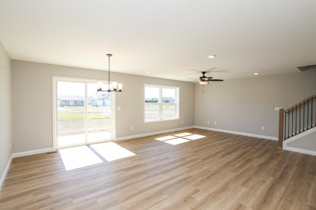 spare room with hardwood / wood-style floors and ceiling fan with notable chandelier