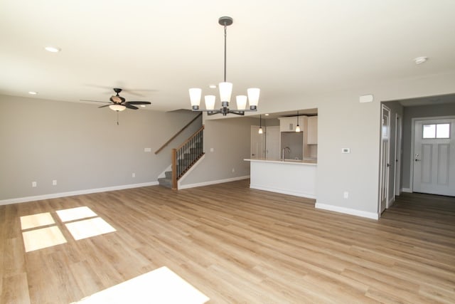 unfurnished living room featuring light hardwood / wood-style floors, sink, and ceiling fan with notable chandelier