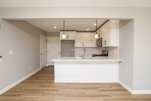 kitchen featuring white cabinets, hanging light fixtures, light hardwood / wood-style flooring, and range