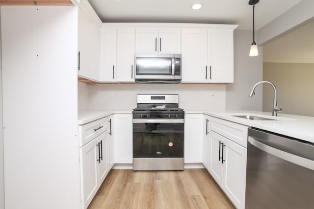 kitchen featuring appliances with stainless steel finishes, sink, light hardwood / wood-style flooring, and white cabinetry