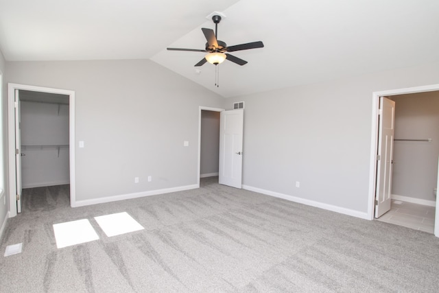 unfurnished bedroom with a closet, a walk in closet, lofted ceiling, ceiling fan, and ensuite bathroom