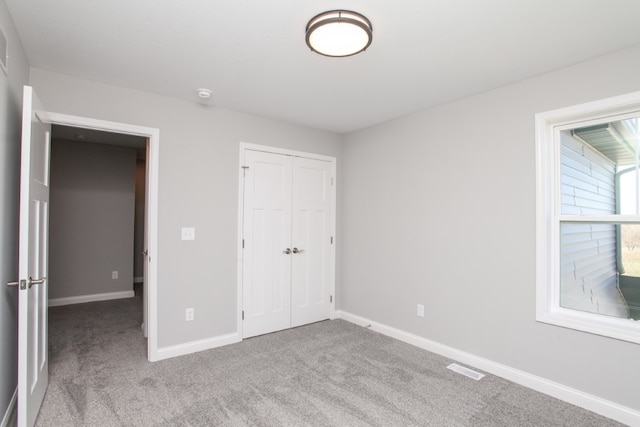 unfurnished bedroom with a closet and light colored carpet