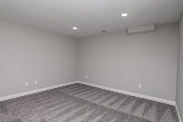 empty room featuring a wall mounted air conditioner and carpet flooring